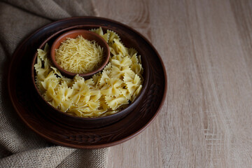 Different types of pasta lie in brown vintage plates on a wooden table and burlap