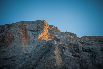 ock face of the Croda del Becco with a cross on the top towards sunset, Braies Lake, South Tyrol, Italy. Concept: awesome dolomitic landscape, unesco world heritage