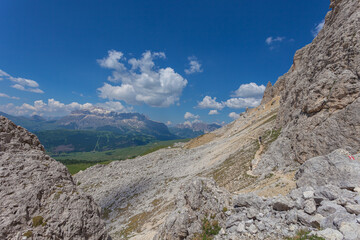 Path at the base of a wall with the Dolomite panorama of Sella massif in the background, Settsass, Dolomites, Italy