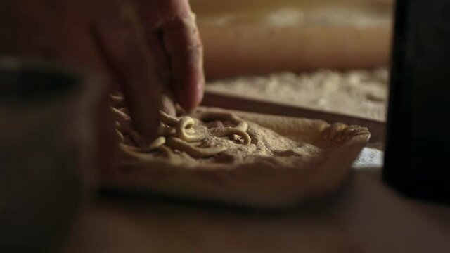 Woman prepares homemade pasta. Slow motion close up of bio flour and pici pasta, the typical tuscany food. Concept of bio, italy, food, home cooking. 