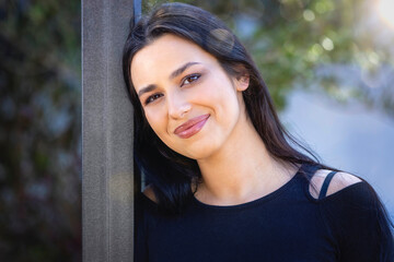 Portrait of a beautiful, smiling woman with long, black hair in warm sunlight