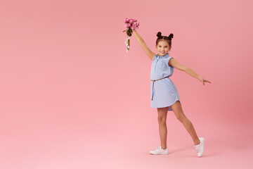 happy little girl holds bouquet of roses and runs on pink background. Mother's day.