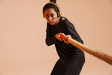Athletic african american woman working out with battle rope