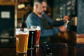 barman standing in bar. He is serving craft beer