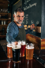 barman standing in bar. He is serving craft beer