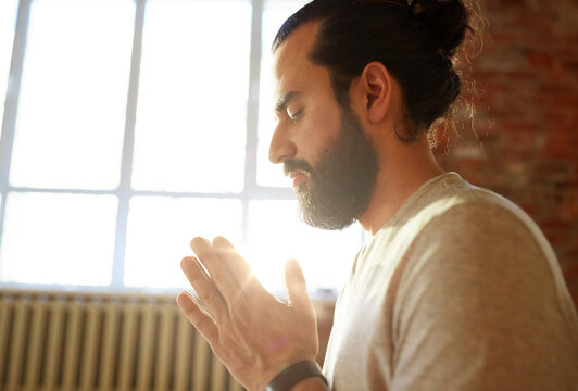 religion, faith and people concept - close up of woman meditating or praying at yoga studio