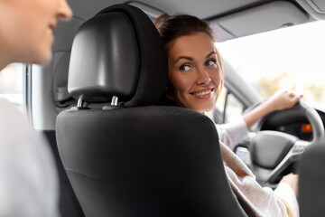transportation, vehicle and people concept - happy smiling female driver driving car with passenger