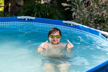 Man in glasses in the summer in a pool showing middle finger, fuck you, provocation and rude...