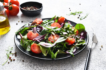 Mix salad with tomatoes, onions and olive oil in a black plate. Detox menu. The keto diet.