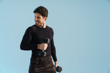 Smiling athletic sportsman working out with dumbbells