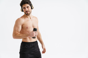 Shirtless athletic sportsman in headphones posing with water bottle