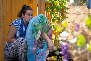 A girl with a displeased face sits inflating a circle for the pool