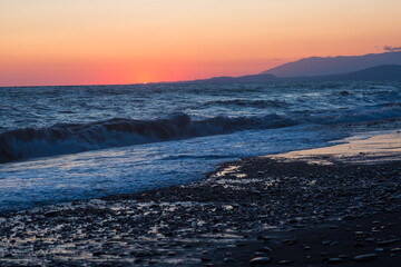 beautiful sunset by the sea with strong waves
