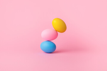 three colorful easter eggs balancing over pink background, balance concept