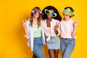Photo of nice optimistic three ladies show v-sign wear spectacles white shirt isolated on bright yellow color background