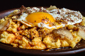 Chickpea puree with corn, fried egg, ghee and pepper, pork rinds and zaatar spices.