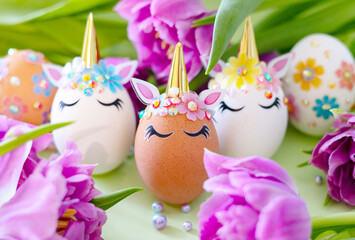brown and white Easter eggs decorated in the form of unicorns on a green and yellow background with bouquet of tulips, a minimal creative concept of a happy Easter