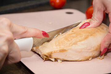 woman cuts boiled chicken breast into small pieces. homemade pizza cooking concept.