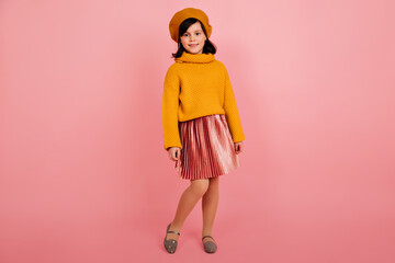 Full length shot of preteen girl in skirt and sweater. Studio photo of cute child isolated on pink...