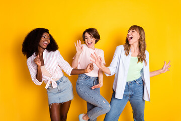 Photo of three charming excited positive girls enjoy free time vacation disco isolated on yellow...
