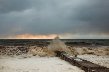 Storm waves near the shore on the beach. In the foreground, breakwaters.
