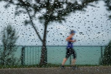 Jogger behind a window covered in raindrops