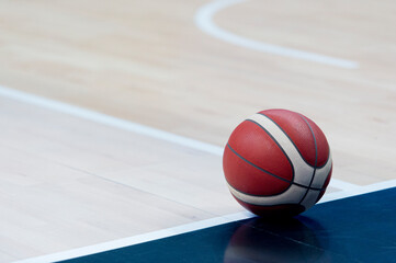 An official orange ball on a hardwood basketball court
