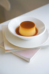 A plate of homemade caramel custard pudding on a book.