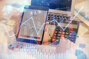 Double exposure of man's hands holding and using a digital device and forex graph drawing. Financial market concept.