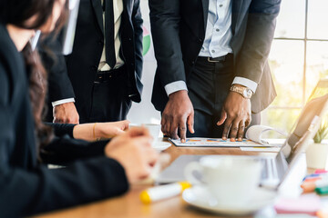 Close-up hands of African businessman planning and discuss with Caucasian colleagues that looking on documents at an internal business group meeting. Diversity of business people.
