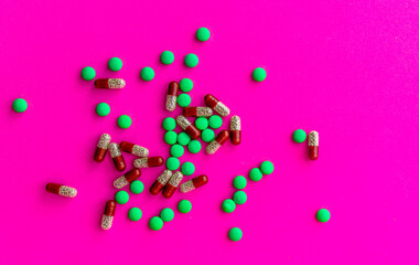 a bunch of different pills vitamins pills and capsules are lying on the table on a pink background close up view from above