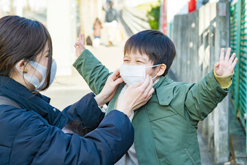 外出先で子供のマスクを整える母親 © maru54