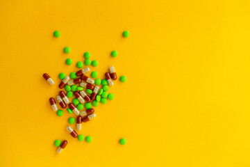 a bunch of different pills vitamins pills and capsules are lying on the table on a yellow background close up view from above