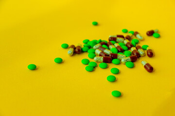 a bunch of different pills vitamins pills and capsules are lying on the table on a yellow background close up view from above