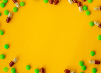 Different tablets and capsules on a yellow background Flat lay