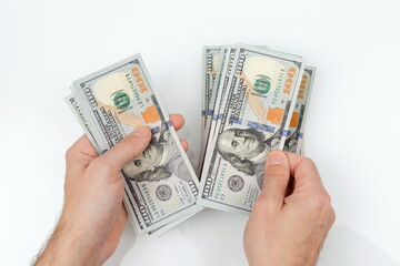 Men's hands hold and count hundred dollar bills on white background. Successful man considers salary.