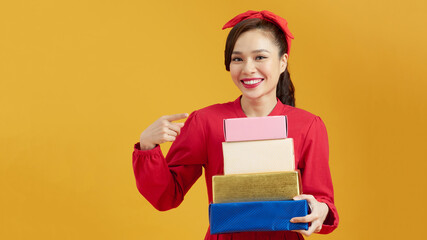 Smiling woman with many gift boxes on background