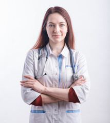 Portrait of a young female doctor in a white uniform who crossed her arms in the studio on a white background