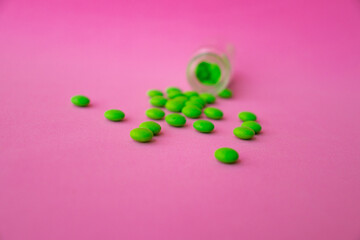 green pills on a pink background close up top view