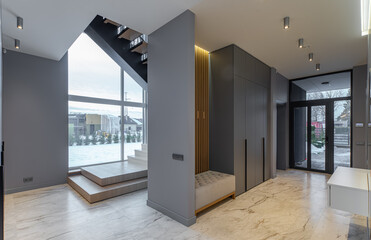 Interior of entrance hall with staircase in luxury house. Grey tones.