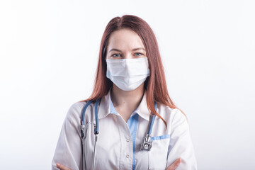 Portrait of a female doctor in a white uniform with a medical mask on her face in the studio on a white background