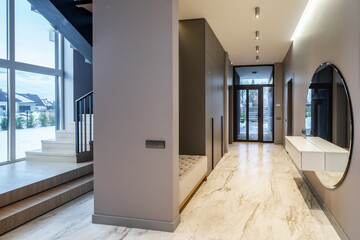 Interior of entrance hall with staircase in luxury house. Grey tones.