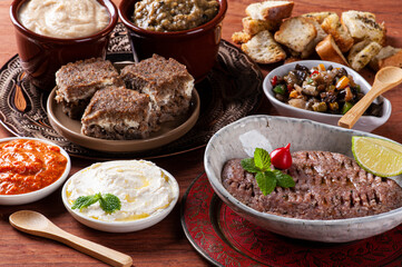 .Meze is an oriental set of appetizers served in small bowls with babaganoush, curd, hummus, muhammara and kibbeh