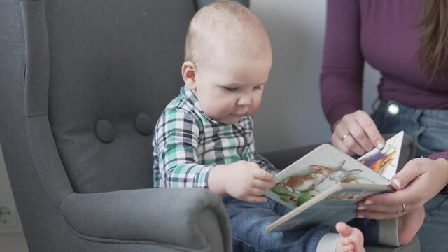 Mom shows a picture book to a little kid at home.