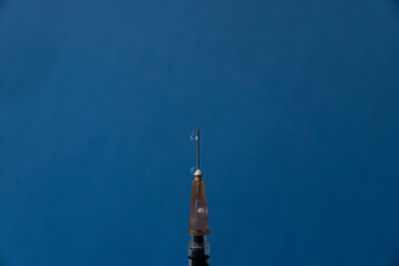Obraz premium The needle of a syringe with a vaccine close-up on a blue background