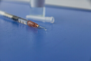 a syringe with a vaccine and ampoules with a vaccine against infections close-up on a blue background