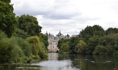 Fototapeta na wymiar Scorcio di Londra all'orizzonte incorniciato da alberi fitti e verdi - vista dal fiume nel parco 