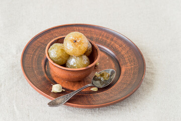 Indian gooseberry (amla) with honey in a clay bowl. A source of vitamins and minerals. Used to boost immunity in Ayurveda. Selective focus.