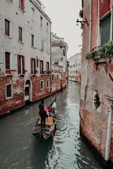 Fototapeta na wymiar Gondoliere che trasporta turisti lungo i canali di Venezia