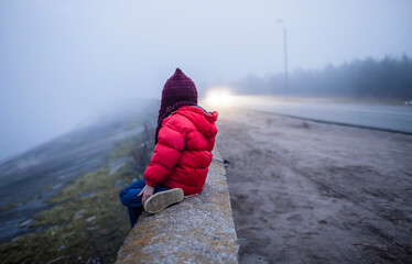 Girl walking alone along road in spring foggy day, uncertainty and hope concept, lifestyle outdoor....